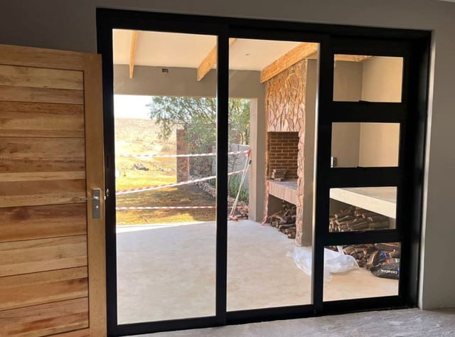 Black aluminium sliding door and window unit with awning windows overlooking a covered patio
