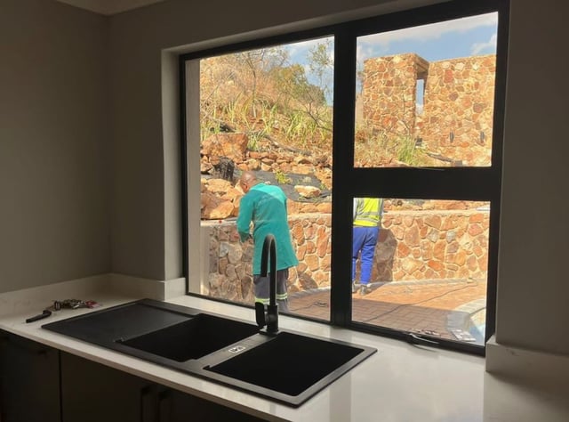 Black aluminium window frame installed above a kitchen sink in a modern home
