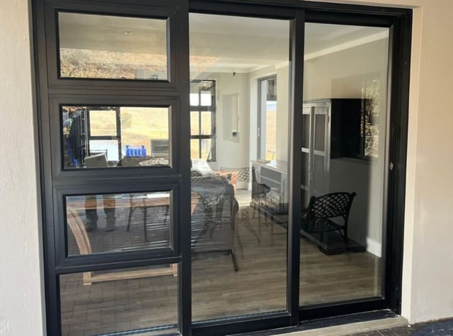 Black-framed aluminium sliding doors and awning windows installed in a modern home